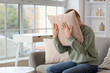 © Pixel-Shot - Mature woman screaming in pillow on sofa at home