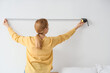 © Pixel-Shot - Mature woman measuring light wall in bedroom, back view
