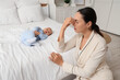 © Pixel-Shot - Tired mother with her baby suffering from postnatal depression in bedroom