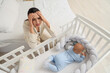 © Pixel-Shot - Young woman with her baby in crib suffering from postnatal depression at home, top view
