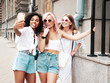 © halayalex - Three young beautiful smiling hipster female in trendy summer clothes.Sexy carefree multiracial women posing on the street background.Positive models having fun in sunglasses. Taking selfie photos