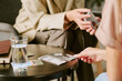 © AnnaStills - Caucasian middle aged woman holding psychological test cards while sitting with another Caucasian middle aged woman during therapy session, glass of water and notebook on table