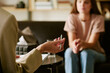 © AnnaStills - Caucasian young adult woman sitting on couch listening to middle aged Caucasian man holding pen during psychological counseling session in office setting