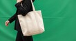 © Selene Studio - Person in black blazer carrying a canvas tote bag against a green background, Woman, Canvas bag, Fabric bag