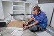 © juraj - Man assembling and installing new diy furniture at home using a hammer and instructions