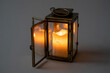 © RubinaAkter - Antique brass lantern with lit candle inside casting warm glow