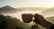 © Nazlykhan - Peaceful morning in nature: hand holding coffee mug with mountain view at sunrise