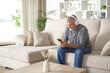 © Antonioguillem - Middle aged man wearing headphone using phone at home