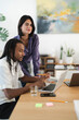 © Studio Marmellata - A diverse male and female team works together in a bright office. The man types on a laptop. The woman stands behind him, pointing at the screen and smiling at the viewer.
