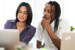 © Studio Marmellata - Two diverse young professionals collaborate on a project, looking at a laptop screen. They are engaged in discussion and problem-solving in a modern office setting.