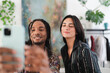 © Studio Marmellata - A diverse couple, a Black man with dreadlocks and a woman, smiles while taking a selfie with a smartphone. They are happy, capturing a moment together.