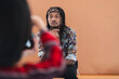 © Studio Marmellata - Young Black man with dreadlocks and a headband poses for a photo. He sits in front of a plain background, looking at the camera. A blurred foreground element is visible.