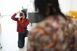 © Studio Marmellata - A smiling female photographer kneels, capturing a portrait of a model in a bright studio. She holds a camera to her eye, focused on her subject, enjoying her work.