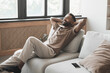 © kite_rin - Satisfied handsome young man relaxing on sofa at home in living room, resting after a hard day work, closed eyes, put hands behind head, smiles happily. Relaxation, self care, enjoy life and holiday