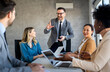 © NDABCREATIVITY - Happy multiethnic businesspeople laughing while collaborating on a new project in an office.