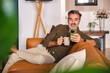 © Westend61 - Man relaxing on sofa at home with coffee and using phone