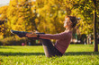 © djoronimo - Adult woman practicing yoga in park in autumn. Healthy lifestyle. Navasana, Boat pose.