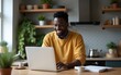 © Thomas - Smiling black guy freelancer stand at kitchen desk read good email message on laptop screen think on advantages proposed by customer. Young afro man hipster chat with friends online from home using pc