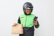 © ArvStd - Happy Asian Delivery Courier in Green Uniform and Helmet With Packages and Phone Ready For Work