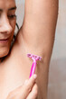 © ADDICTIVE STOCK - Woman shaving her armpit with a pink razor