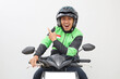 © ArvStd - Asian online taxi driver, male motorbiker wearing jacket and helmet, pointing back at empty space, isolated on white background.