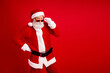 © deagreez - Santa Claus in a festive red outfit posing confidently with a playful expression against a red background