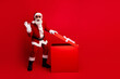 © deagreez - Festive Santa Claus opening a gift box on red background celebrating Christmas and spreading holiday cheer