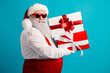 © deagreez - Santa with red suit and hat delivers festive gifts against a blue backdrop creating Christmas cheer and holiday joy