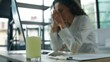 © Yuliia - Close-up glass with remedy water medication pill blurred business woman feeling headache pain with computer in office ill sick tired bad feeling businesswoman female girl worker with liquid painkiller
