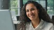 © Yuliia - Indian business woman Hispanic female Arabian ethnic businesswoman working on computer in office looking at camera smiling happy positive lady executive worker entrepreneur manager work online at desk