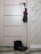 © Anna - A folding umbrella on the front door handle and women's black rubber boots on the floor below