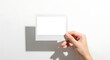 © Mishal - Realistic hand presenting an empty Polaroid photo frame isolated on white. Perfect template for adding custom images or branding layouts.