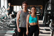 © Home-stock - Happy muscular couple posing in gym, fit man and woman standing in modern gym surrounded by exercise equipment and smiling at camera