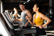 © Home-stock - Focused and energized ,an and woman running on treadmills in bright gym, atmosphere is lively with light streaming through windows