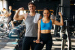 © Home-stock - Strong European man and woman couple posing in modern gym after workout, showing their biceps and smiling at camera