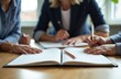 © starush - A group of people collaborating around a table with an open notebook and pens in a bright office setting