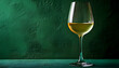 © wolfelarry - Glass of chilled white wine rests on a textured green table. The drink clarity and color are evident against a dark green backdrop, suggesting a sophisticated beverage moment