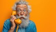 © Tetiana - Eccentric Senior Man In Blue Shirt Having Fun On Vintage 80s Telephone, Making Silly Faces And Expressing Emotions. Elderly Grandfather On Orange Background.