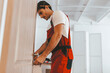 © Prostock-studio - A dedicated worker in red overalls carefully installs door hardware in a contemporary room. The scene emphasizes skill and attention to detail in home improvement.