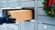 © pufanya - Package delivery man puts box into locker with Christmas wreath during snowfall. Depicts convenient parcel pickup service and the holiday season, useful for articles about shopping or Christmas sales.