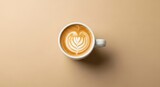 Overhead shot of a latte with heart-shaped latte art in a white mug on a beige background.