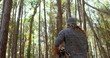 © vectorfusionart - Standing man holding bundle of sticks, wearing knit beanie and sweater in pine forest