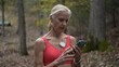 © Robert Peak - Mature woman engages with heart monitoring technology for atrial fibrillation while walking in a wooded area, promoting health