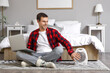 © Pixel-Shot - Young man with laptop and electric fan heater sitting on carpet in bedroom