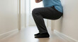 © SYATRI RAWU - A person performing an isometric wall sit exercise in a hallway to build lower body strength and endurance at home