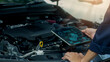© tanakorn - A technician uses a digital tablet to analyze engine data and monitor automotive performance with advanced diagnostic technology. Ideal for smart maintenance, modern vehicle inspection,