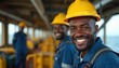 © miss irine - African industrial workers wearing yellow hard hats and blue uniforms on an oil rig or platform at sea. Smiling men at work in the energy industry. Two workers in the foreground and background.