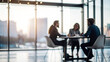 © Hanna - blurred photo of business people sitting around the table in an office, captured from behind and in focus, symbolizing collaboration within company