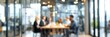 © ffunn - blurred background of a business meeting in a modern office with a glass door and people sitting at a table, a group talking during a conference or meeting.