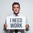 © Nadiia - Serious man in shirt and tie holding I NEED WORK sign against plain studio wall background view face
